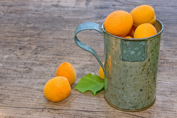Apricots in a cup on a wooden background