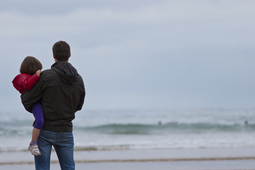 Padre con hija en cuello mirando al mar