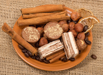 Sweets, cinnamon, nuts and coffee beans on a saucer, on burlap b