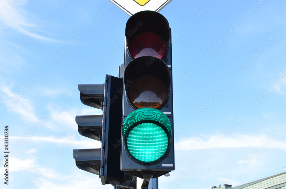 Wall mural green color traffic light blue sky in background