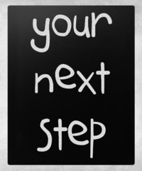 "Your next step" handwritten with white chalk on a blackboard