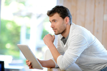 Handsome man relaxing at home with digital tablet