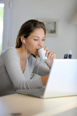 Woman checking email on laptop computer while drinking coffee