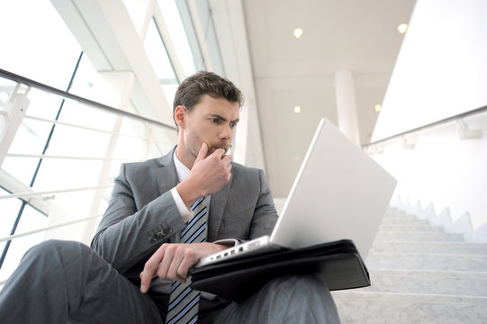 Serious businessman sitting in stairs with laptop