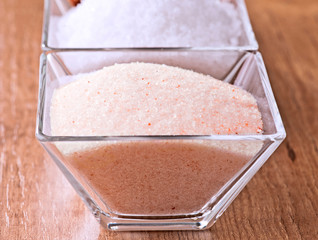 Himalayan pink salt in small bowl of glass. Behind Maldon salt