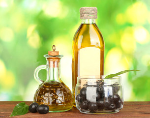 Olive oil bottle and small decanter on green background