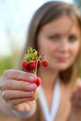 young woman holding wild strawberries