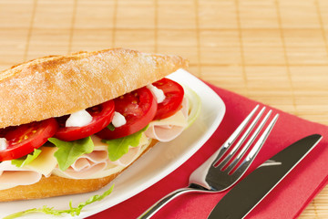 Sandwich with ham, cheese, arugula and tomato