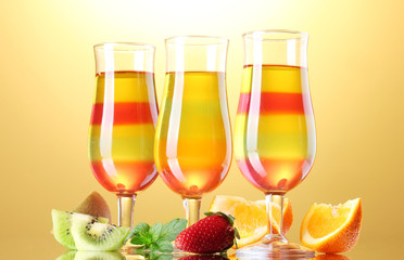 fruit jelly in glasses and fruits on yellow background