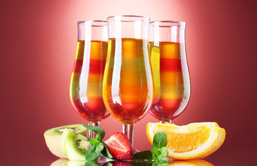 fruit jelly in glasses and fruits on red background