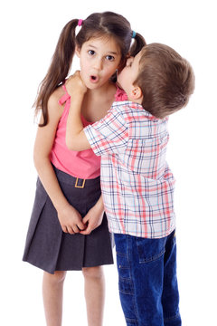Little boy whispering something to girl