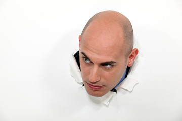 bald man breaking a paper wall with his head