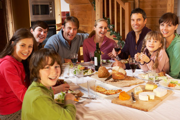 Fototapeta na wymiar Two Familes Enjoying Meal In Alpine Chalet Together