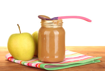 Jar with apple baby food, spoon and apples