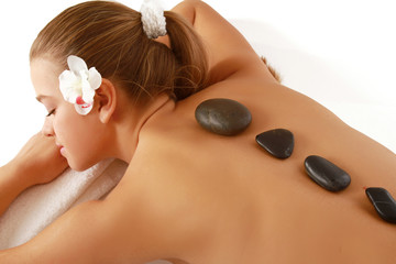 Obraz na płótnie Canvas Pretty woman receiving a therapy with hot stones in spa center