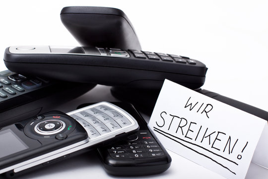 ein stapel mobilteile und handys mit der notiz wir streiken