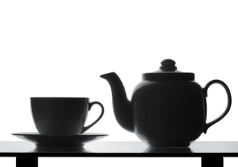 Teapot and cup on table. Silhouette