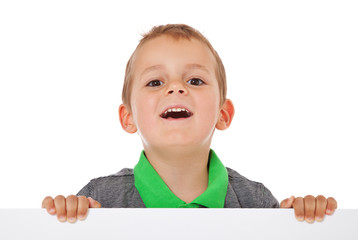 Glücklicher kleiner Junge hinter weißer Wand