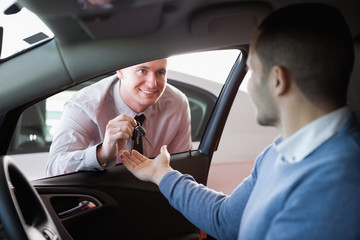 Smiling salesman giving keys to a customer