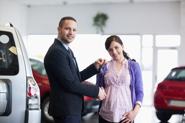 Salesman shaking hand and giving keys to a woman