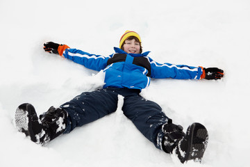 Fototapeta na wymiar Young Boy Making Snow Angel On Slope