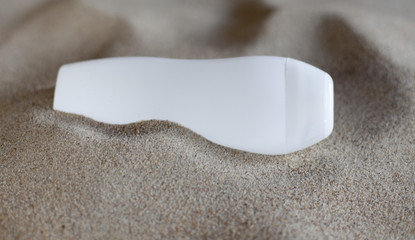 flacon de crème de soin dans le sable