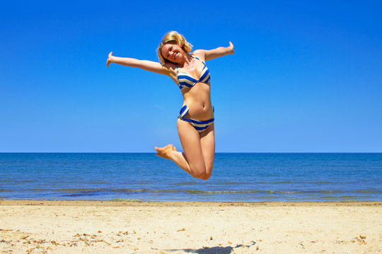 happy girl wearing bikini jumping on beach