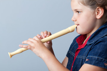 Little girl plays the flute on a grey background © cristovao31