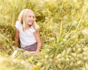 Naklejka na ściany i meble Girl sitting in wheatfield