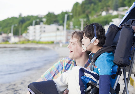 Father enjoying  beach with disabled son