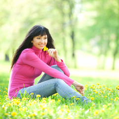 Cute woman in the park with dandelions