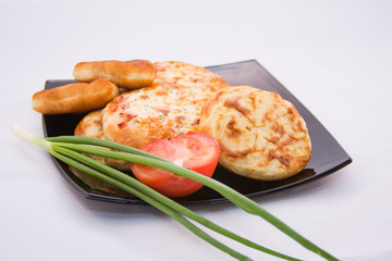 baking on a large platter with ripe tomatoes and green onions on