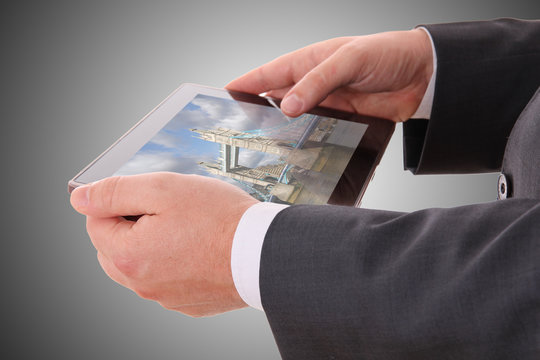 male hand holding a tablet with a photograph of London