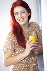 Woman standing by window with juice