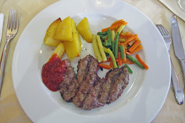dish at the restaurant with meat and French fries, mixed vegetab