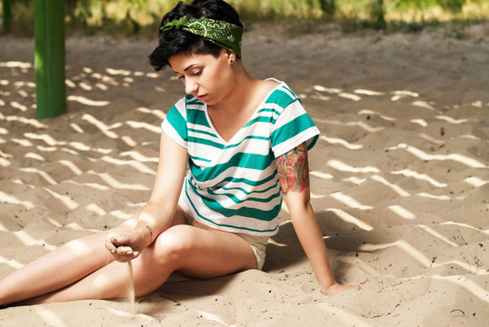 girl with tattoo on the beach pours sand