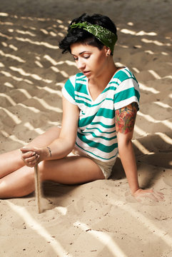 girl with tattoo on the beach pours sand