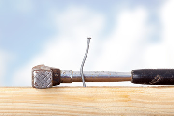 Crooked nail in the wooden board with a hammer