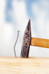 Crooked nail in the wooden board with a hammer