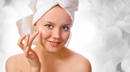 beautiful woman in towel applying cream 