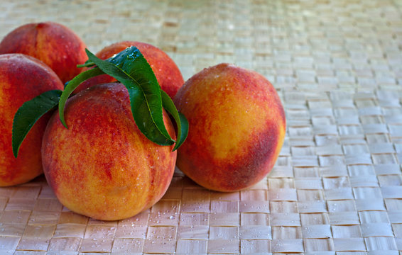 Juicy ripe peaches on raffia background