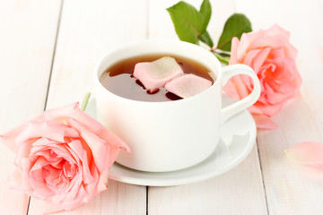 cup of tea with roses on white wooden table