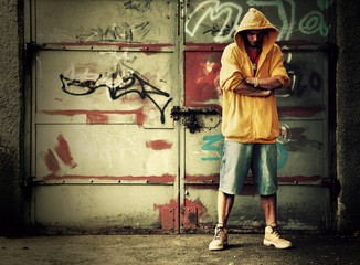 Young man in hooded sweatshirt on grunge wall