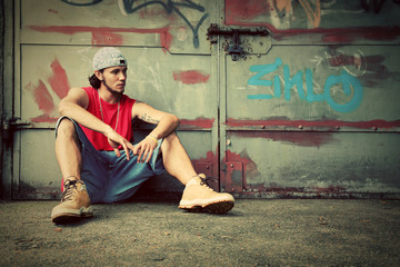 Young man sitting. Grunge graffiti wall