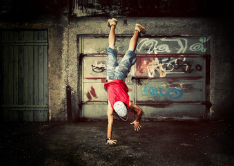 Young man dancing on grunge graffiti wall