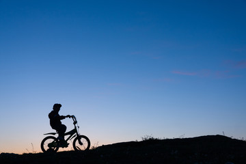 Fototapeta na wymiar Silhouette of boy on bike