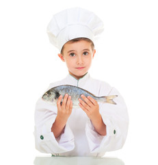 Little boy chef in uniform presenting dorado fish