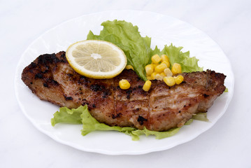 Appetizing juicy fried meat with green salad and marinaded corn