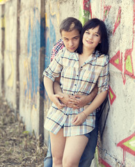 Style teen couple near graffiti background.