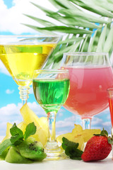 Glasses of cocktails on table on blue sky background